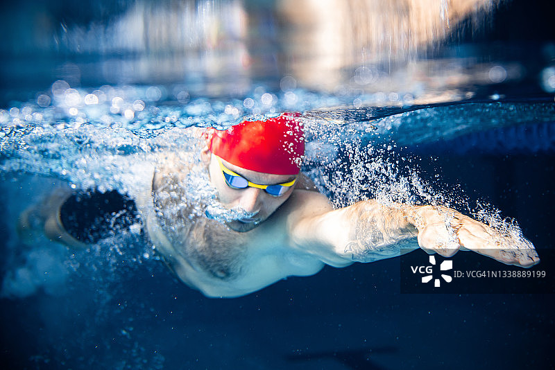 一名男性游泳运动员在室内游泳池练习和训练。水下观察游泳运动的细节。健康的生活方式，动力，能量，运动理念。图片素材