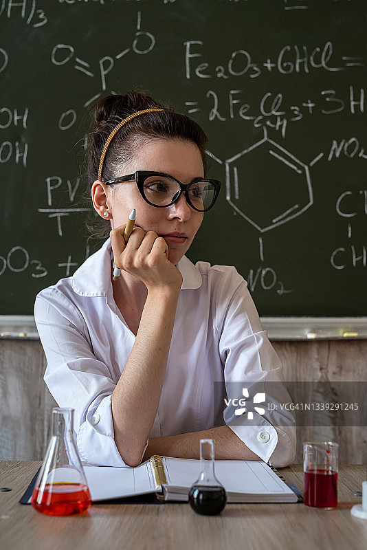 一名化学老师在黑板边的玻璃烧瓶里搅拌液体图片素材