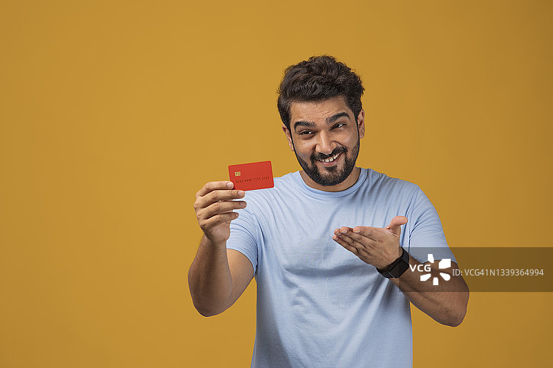 一名男子的肖像在朴素的背景下展示他手中的信用卡。图片素材