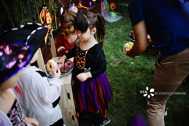 可爱的小孩子在万圣节的游园会上吃着糖果，穿着戏服图片素材
