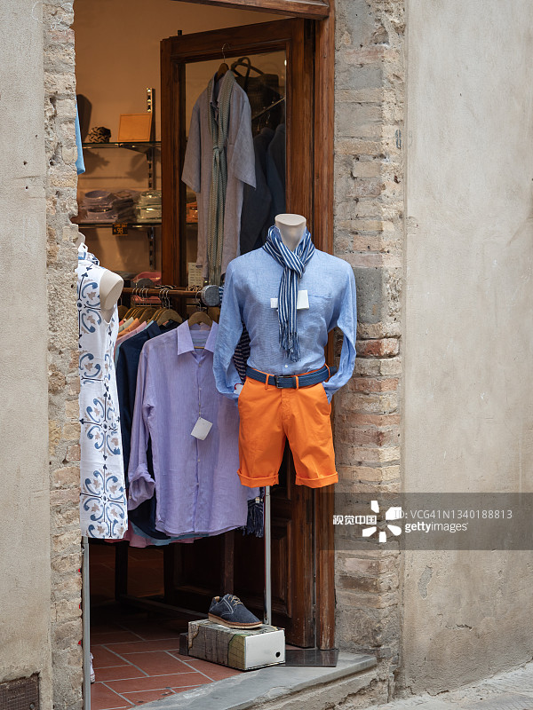 男人体模型展示在一家服装店外面，穿着休闲风格的衬衫，围巾和短裤图片素材