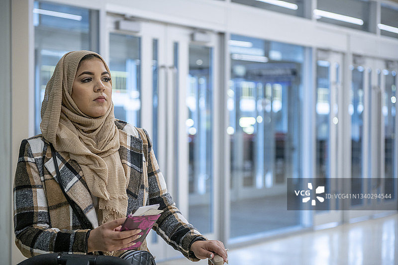 一名穆斯林妇女拿着手机在机场等候图片素材