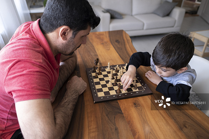 父亲和儿子一起在家里下棋。家人在家里。图片素材