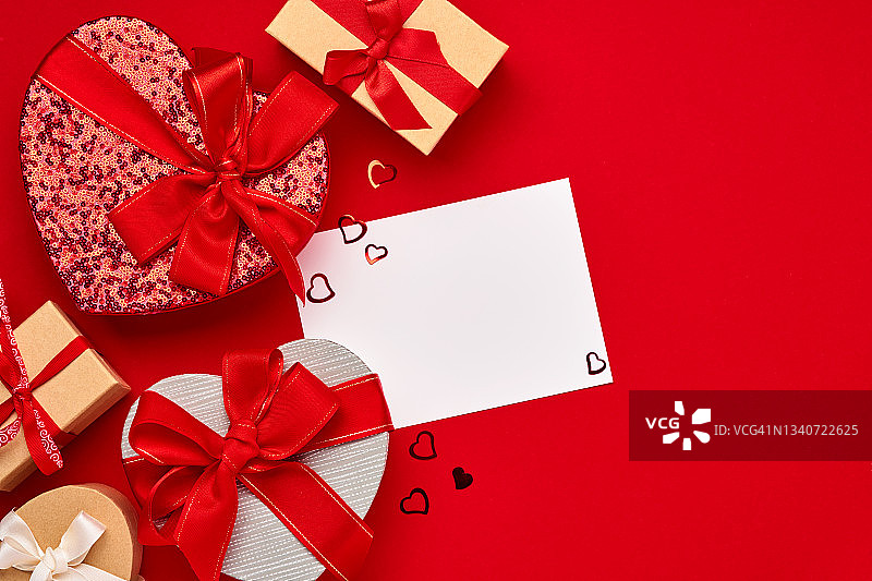 各种选择的礼品盒的形式的心与红色的丝带在红色的背景。情人节概念明信片。顶视图平面布局与复制空间。图片素材