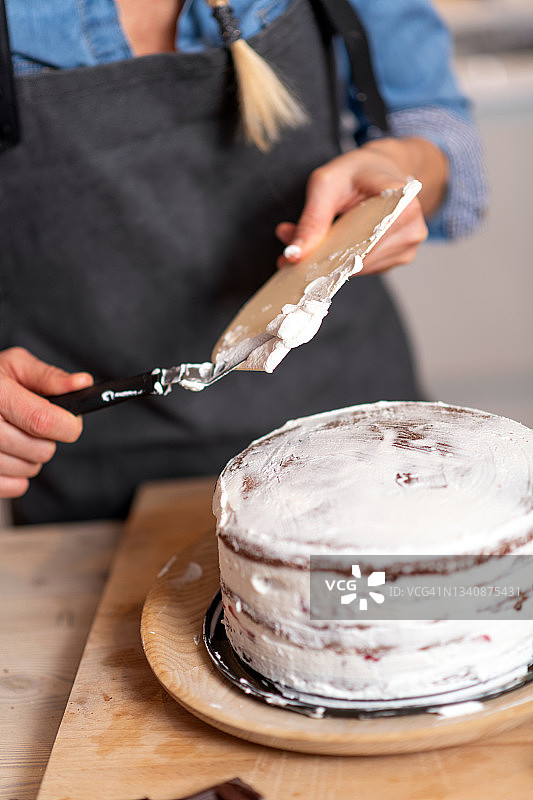 在家烘焙的女人，滴蛋糕准备:涂抹生奶油图片素材