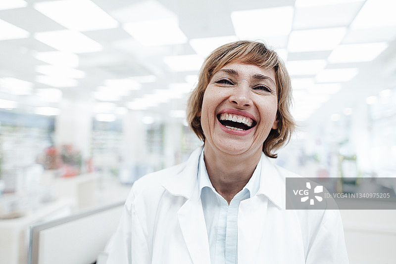 快乐的女药剂师在药店里大笑图片素材