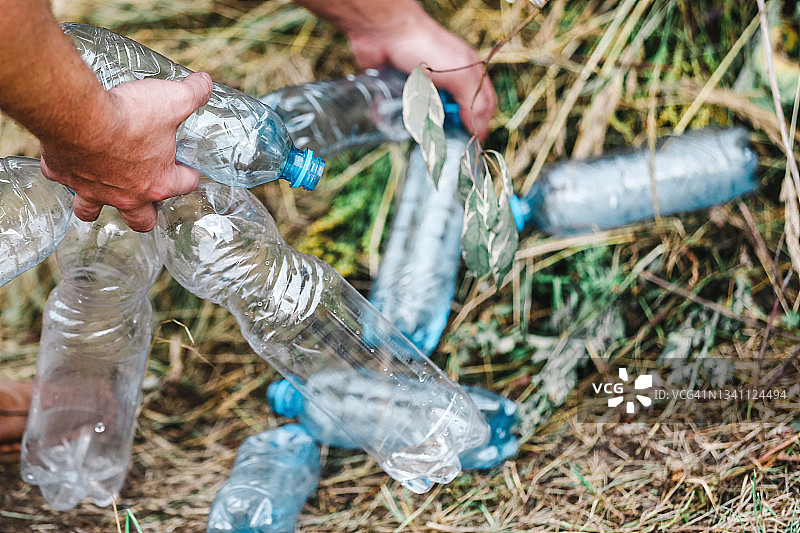 男子的手从干草中抓取一堆蓝色塑料瓶背景图片素材