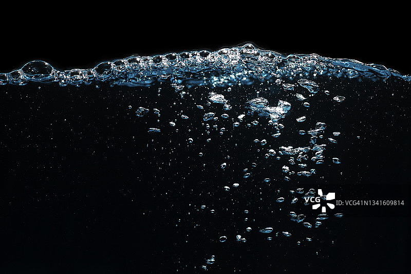 水面与波纹和泡沫浮在黑色背景。图片素材