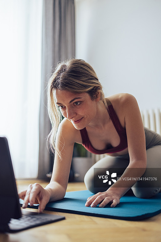 快乐健身女性在平板电脑上观看训练视频图片素材