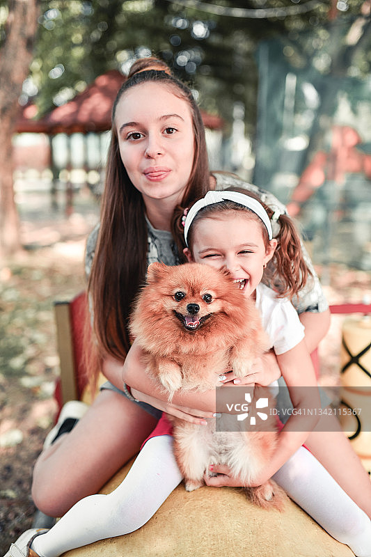 微笑的姐妹和她们可爱的博美犬图片素材
