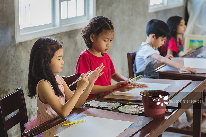 一群在家里或小学用铅笔在纸上画画的亚洲孩子图片素材