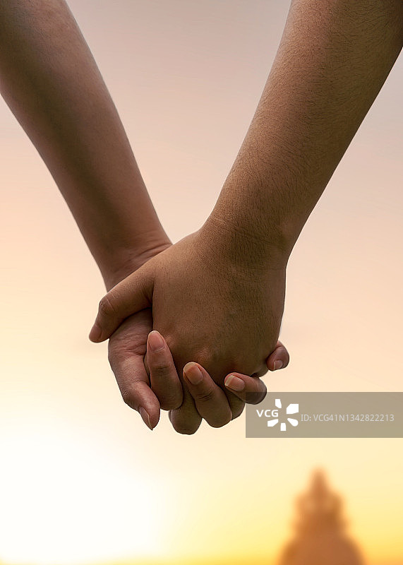 一对陌生的情侣手拉着手的后视图。图片素材