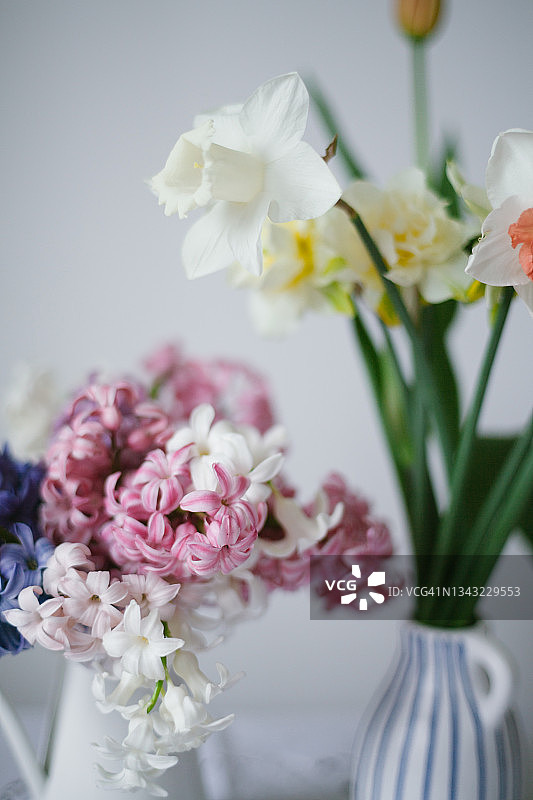 白色桌子上的白色花瓶里的五彩缤纷的春天花朵的特写图片素材