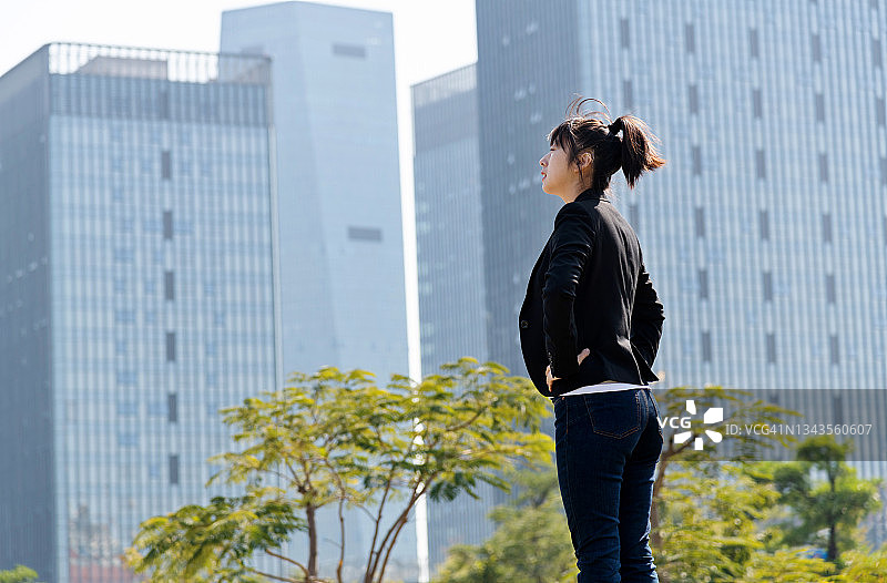 女商人叉腰站在摩天大楼前图片素材
