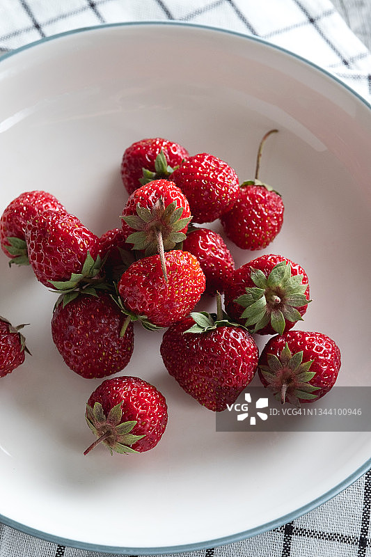 红色、成熟、多汁、美味的草莓放在碗或陶瓷盘子里，放在木制背景或桌子上。素食的概念，素食和生食的食物和饮食。图片素材