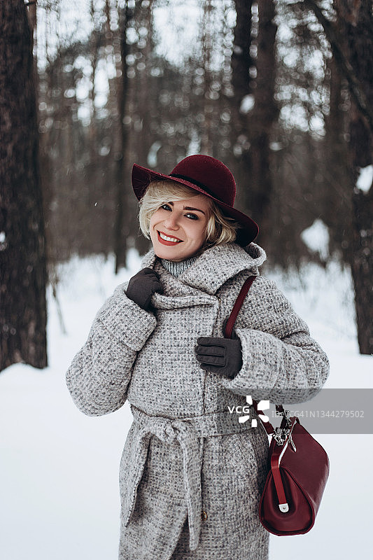 年轻微笑的女人与手提袋在森林中摆姿势。图片素材