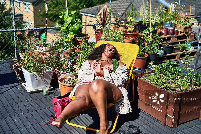 一个女人在屋顶露台的躺椅上大笑图片素材
