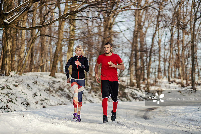 雪天，一对运动情侣在大自然中一起慢跑。恋爱，冬季健身，有氧运动图片素材