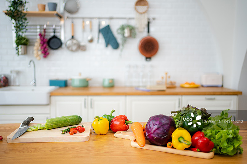 有蔬菜的厨房桌子和准备沙拉的切菜板。图片素材