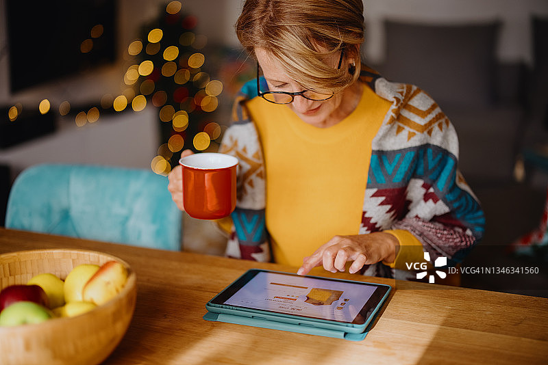 成熟女性用数码平板电脑在圣诞网上购物图片素材