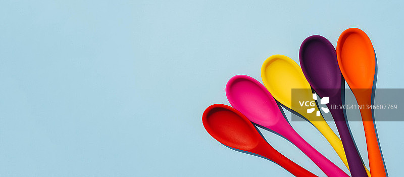 色彩鲜艳的勺子放在彩色背景上。图片素材