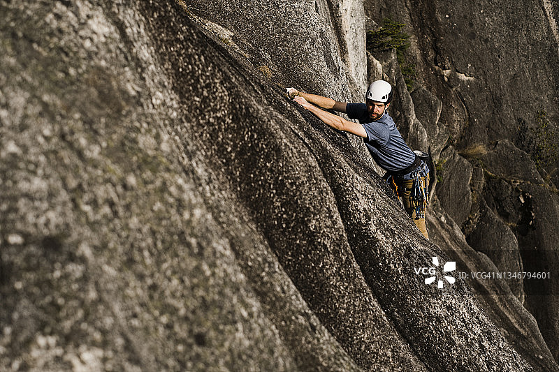 一名男性攀岩者爬上了一块巨大的花岗岩图片素材