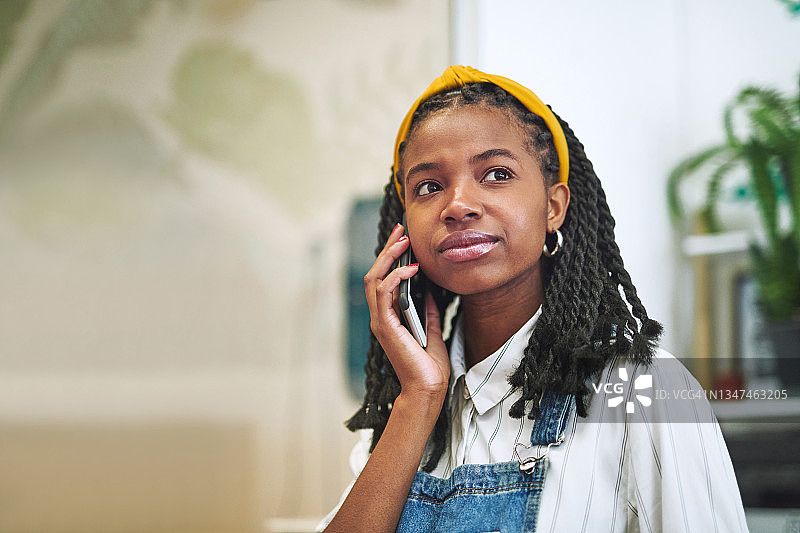 一个年轻迷人的女商人独自站在办公室里用手机图片素材