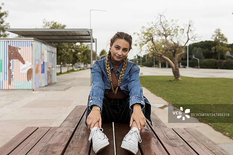 一个年轻女人坐在公园的长椅上图片素材
