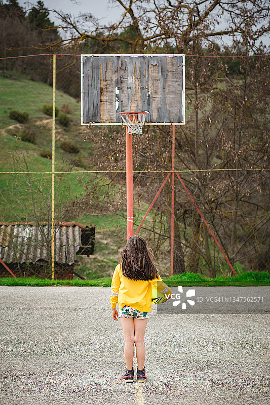 一个女孩在农村学校的篮球场图片素材