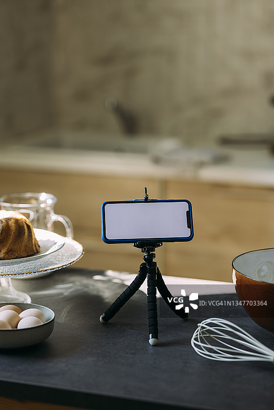 糕点厨师的视频博客:厨房台面上三脚架上的智能手机图片素材