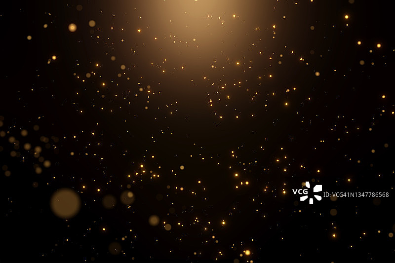 许多节日的金色尘埃在黑色的背景与温暖的聚光灯。新年或生日庆祝的概念。完美的背景为您的设计图片素材