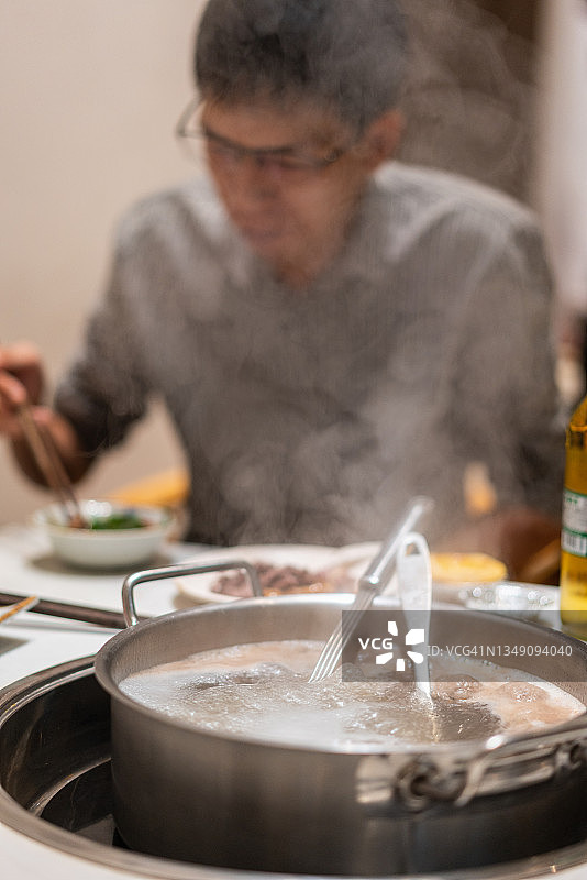 一个亚洲人在牛肉火锅店里喝酒图片素材