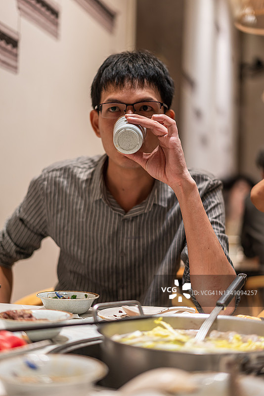 一名亚洲男子在牛肉火锅店喝酒图片素材