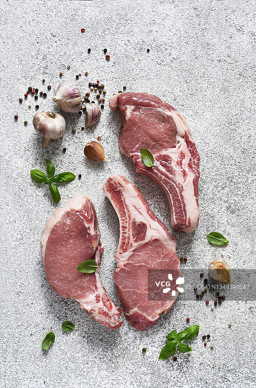新鲜的肉。把肋骨放在木板上，在浅色背景上放上香料。猪肉牛排。图片素材