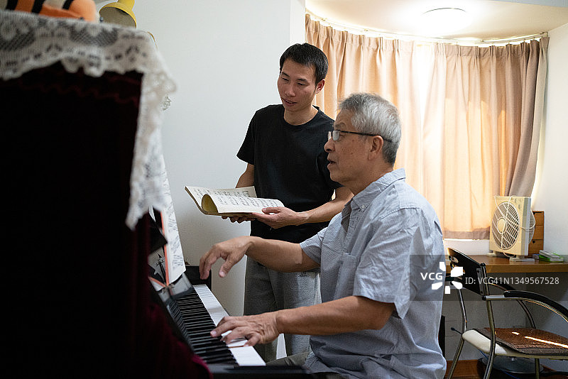 老人的父亲和儿子正在房间里弹钢琴图片素材