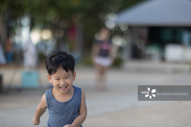 快乐的亚洲男孩在操场上奔跑图片素材