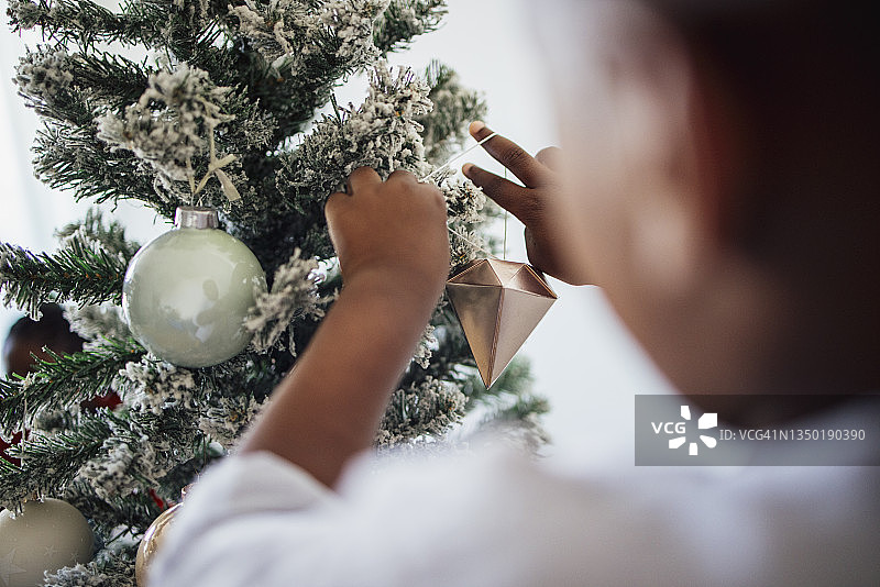 一个无名男孩在家里装饰圣诞树图片素材