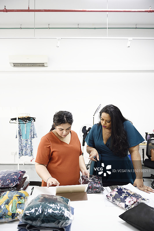 两个女人用平板电脑打包订购的衣服图片素材