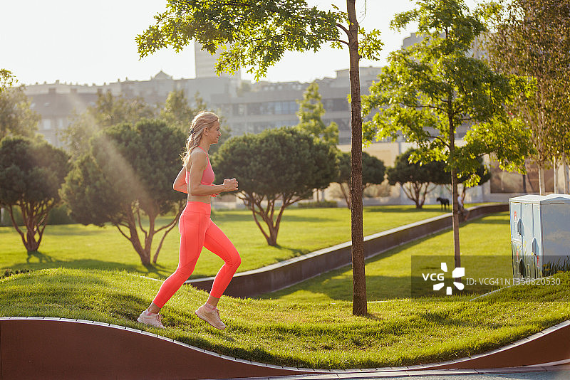 身穿运动服的女子在公园指定跑道上慢跑图片素材