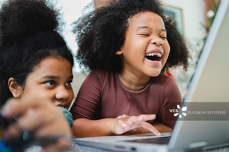 两个非洲裔美国女孩在家里用电脑在线学习的同时，一起玩得很开心。图片素材