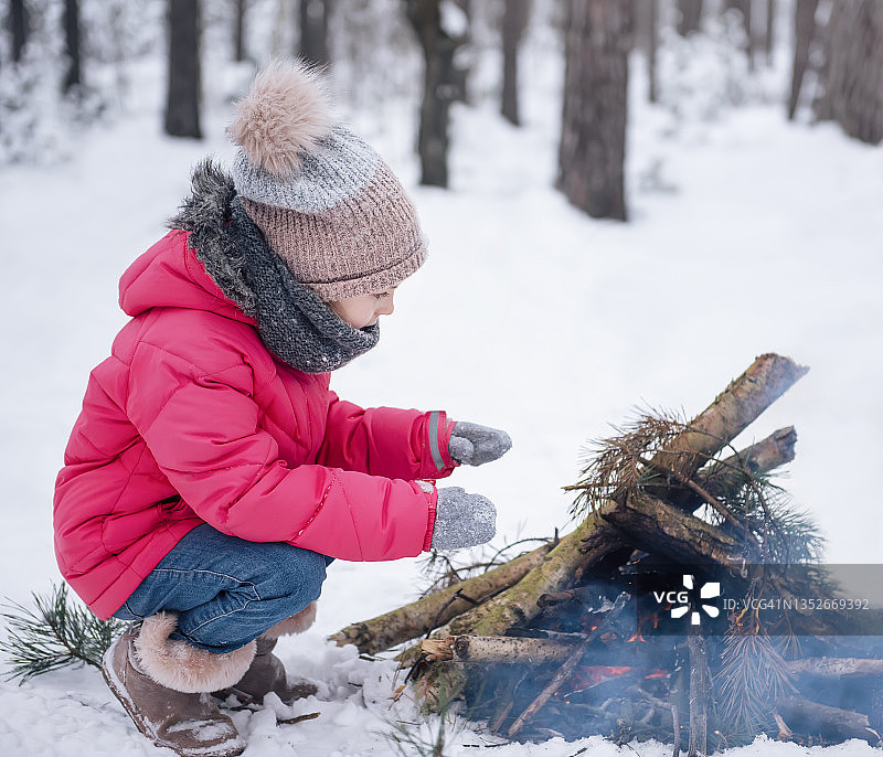小女孩穿着鲜艳的夹克在冬天的森林里玩耍图片素材