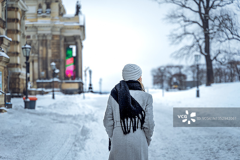 一个女人走在下雪的街道上图片素材