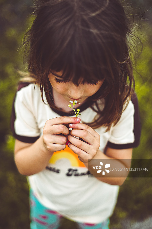 可爱的小嬉皮士女孩在复古彩虹衬衫持有一朵野花图片素材