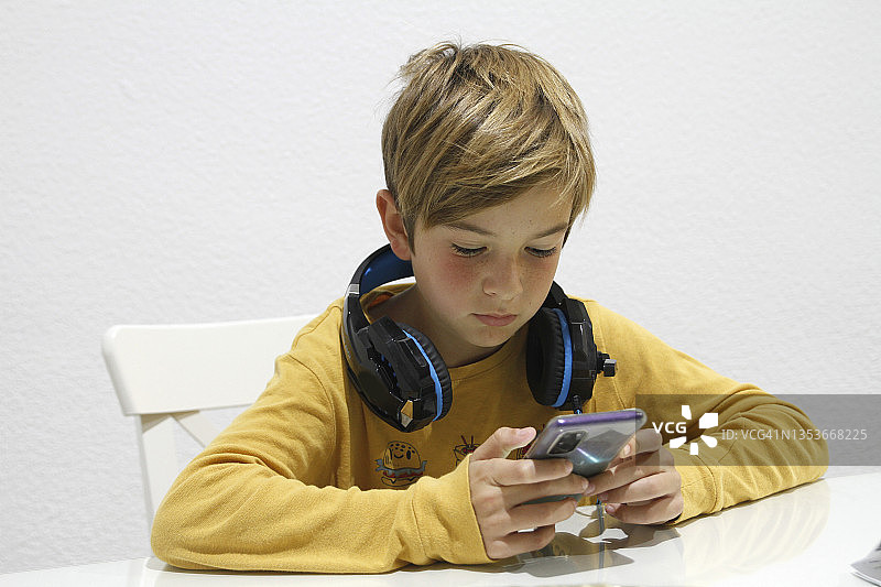 带着耳机和智能手机的专注男孩图片素材