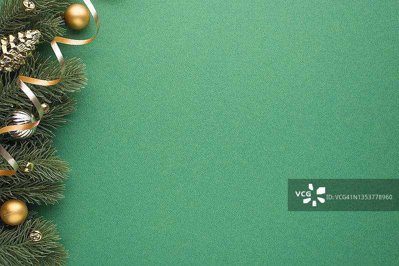 俯视图照片的金和银圣诞树球玩具圆锥小铃铛和蛇在松枝上孤立的绿色背景与copyspace图片素材