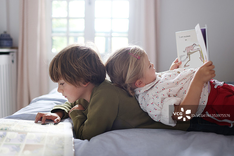 一对兄妹在家里的一张床上一起读书图片素材