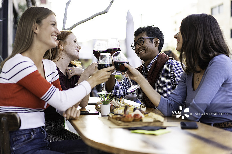 多种族的朋友在户外酒吧喝红酒-食物和饮料的生活理念，快乐的人们在酒吧一起享受乐趣-明亮的滤镜聚焦在背景中的男人图片素材