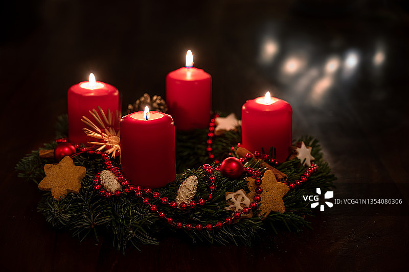 装饰的圣诞花环从冷杉树枝与红色点燃的蜡烛，圣诞球和星星饼干，一些模糊的灯光在黑暗的背景，复制空间，选定的焦点图片素材