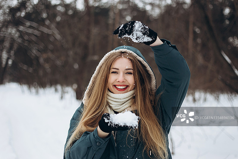 可爱的年轻女子，满手掌的雪有乐趣和微笑。图片素材