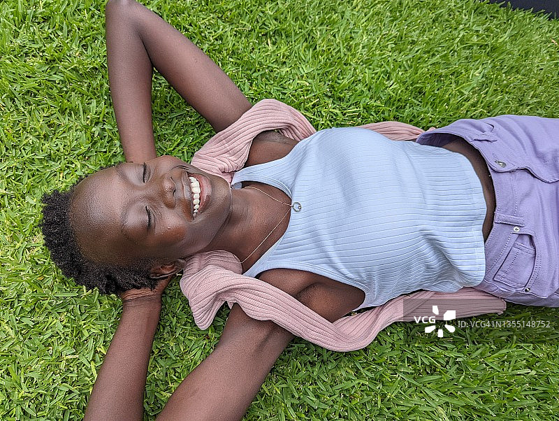 年轻女子微笑着躺在外面的草地上图片素材